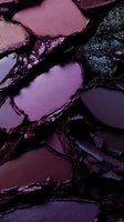 Crushed purple and burgundy eyeshadow palette showing metallic shimmer texture and powder fragments in macro photography for beauty and cosmetics background.