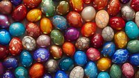 Colorful crackle-glazed ceramic beads in vibrant orange, blue, turquoise, red, and green hues create abstract pattern background for jewelry making and craft projects.