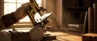 Vintage brass microscope on wooden desk in warm sunlit study room with old books creating scholarly academic atmosphere for scientific research and education.