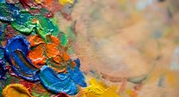 Vibrant oil paint palette with thick brushstrokes in blue, green, orange and yellow colors on artist canvas background for creative projects.