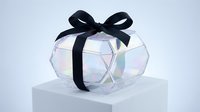Transparent glass sphere with black ribbon bow on white pedestal, holographic iridescent surface reflecting rainbow colors for luxury gift concepts.