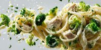 Creamy fettuccine pasta with tender chicken pieces and fresh broccoli florets in a rich garlic sauce, garnished with herbs and parmesan cheese.
