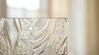 Close-up of clear crystal glass with intricate swirled texture pattern catching natural light in elegant home interior setting for luxury decor concepts.
