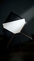 Elegant black envelope with white card emerging, gold trim detail on dark background for luxury correspondence and invitation designs.