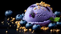 Purple blueberry ice cream scoop garnished with fresh berries, crunchy cookie crumbles and mint leaf on dark background, macro food photography.