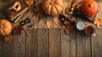 Autumn flat lay with orange pumpkins, fall leaves, candles and seasonal decorations on rustic wooden background with copy space for text.