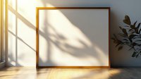 Empty gold frame on white wall with natural window light casting plant shadow, wooden floor with sunlight reflection creates minimalist home interior scene.