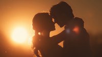 Romantic couple silhouettes embracing at golden sunset creating intimate moment for love and relationship concepts in warm atmospheric lighting.