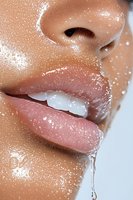 Close up of wet glossy lips with water drops and splashes on glowing hydrated skin, showing natural beauty and skincare results for cosmetic advertising.