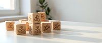 Wooden blocks with business icons on white table in modern office interior for corporate strategy and planning concepts.