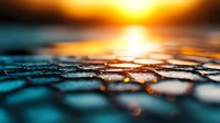 Dramatic sunset reflection on textured water surface creates abstract pattern with golden light and teal tones, macro photography showing ripples and bokeh effect.