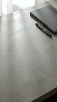Minimalist concrete desk with a dark notebook and pen, soft natural light, clean workspace concept for business and productivity.