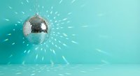 Shiny disco ball reflecting light rays on turquoise background creating sparkle effect for party celebration nightclub entertainment dance floor atmosphere.