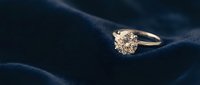 Elegant diamond engagement ring with brilliant cut stone on luxurious dark blue silk fabric background for wedding and jewelry concepts.