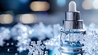 Glass dropper bottle with clear serum among sparkling snowflakes and ice crystals against blurred winter bokeh background, skincare and beauty concept.