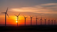 Wind turbines silhouetted against dramatic sunset sky generating renewable energy for sustainable power production and environmental conservation.