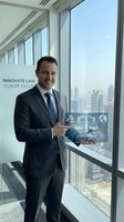 Professional businessman in dark suit presenting digital legal technology hologram with scales of justice in modern office overlooking city skyline.