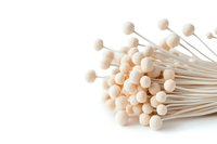 Delicate white reed diffuser sticks with round ball tops arranged in bunch on white background, isolated decorative elements for home fragrance and aromatherapy.
