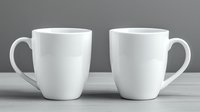 Two white ceramic coffee mugs on wooden surface against gray background, ideal for mockups in minimalist kitchen or office settings.