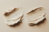 Creamy beige foundation or concealer cosmetic texture smears on neutral background showing smooth makeup product consistency and application strokes.