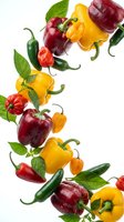 Colorful bell peppers and hot chili peppers with fresh basil leaves falling on white background. Organic vegetables for cooking and healthy eating.