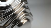Stack of glossy magazines with curved pages creating dynamic flowing lines and shadows on neutral background for publishing and media concepts.