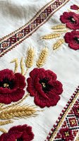 Traditional Ukrainian embroidered linen textile with red poppy flowers and wheat ears in folk art style for cultural heritage and handicraft projects.
