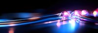 Glowing blue and pink light trails with bokeh effects create dynamic motion against dark background, suitable for technology and innovation concepts.