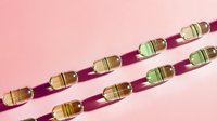 Colorful glass beads casting creative diagonal shadows on pink background, minimalist composition with geometric pattern and light refraction effects.