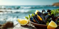 Fresh mussels served in rustic bowl with lemon wedges on wooden surface against blurred seascape background, showcasing coastal cuisine.