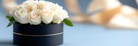 Elegant white roses arranged in black round box on modern table surface creating luxurious floral display for special occasions and romantic gestures.