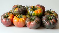 Fresh heirloom tomatoes in various shades of red, orange, and purple arranged on white background, showing natural organic produce with distinctive shapes.