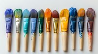 Colorful art paint brushes with vibrant bristles arranged in rainbow order on white background, wooden handles with paint drips, isolated for creative design projects.