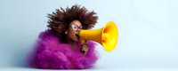 Young African American woman with natural curly hair and glasses emerging from purple smoke cloud speaking through yellow megaphone against light background.