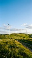 Wind turbines on rolling green hills with dirt path, generating clean renewable energy under blue sky with clouds.