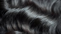 Close-up of glossy black wavy hair texture showing natural shine and movement, ideal for beauty, haircare, and salon advertising.