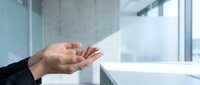 Professional businesswoman hands releasing white paper airplane in modern office space with natural lighting for corporate freedom concepts.