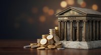 Classical bank building with golden coins stacked nearby representing financial services, banking industry, investment and economic growth concepts.