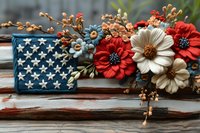 Rustic American flag decoration with red and white fabric flowers, blue berries, and natural elements arranged on weathered wood, patriotic home decor for July 4th celebration.