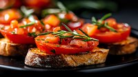 Fresh bruschetta with juicy tomato slices and aromatic rosemary on crusty toasted bread, served on dark plate. Close-up food photography with selective focus.