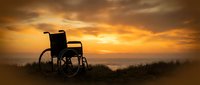Silhouette of empty wheelchair against dramatic golden sunset sky with clouds, symbolizing hope, recovery, and resilience for healthcare and wellness campaigns.