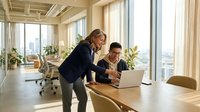 Professional businesswoman and businessman collaborating on laptop in modern office with city view, discussing project strategy and teamwork.
