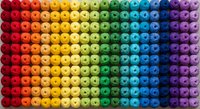 Colorful rainbow gradient of small round beads arranged in organized rows creating vibrant spectrum pattern for craft projects and creative designs.