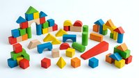 Colorful wooden building blocks set with geometric shapes including cubes, cylinders, triangles and rectangles isolated on white background for educational play.
