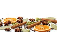 Aromatic spices and dried orange slices scattered on white background for culinary designs, recipes, cooking blogs, seasonal decorations and food styling.