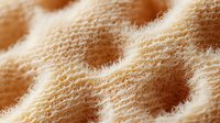 Extreme macro close up of beige woolen fabric texture showing detailed fibers and soft material structure. Natural textile background pattern.