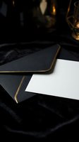 Elegant black leather portfolio with gold trim and blank white paper on dark marble surface with warm ambient lighting for luxury business presentations.