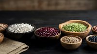 Assorted legumes and grains in wooden bowls on rustic dark surface. Healthy protein sources including lentils, beans, chickpeas for cooking and nutrition.
