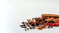 Aromatic spices collection with cinnamon sticks, star anise, cloves and chili pepper on white background for culinary and cooking projects.