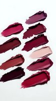 Lipstick smears in various shades of burgundy, wine, and pink on white background showcase rich cosmetic textures and pigments for beauty and makeup artistry.